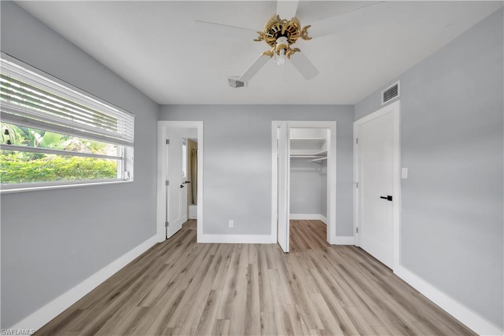 Unfurnished bedroom featuring light wood-type flooring, a walk in closet, and ceiling fan