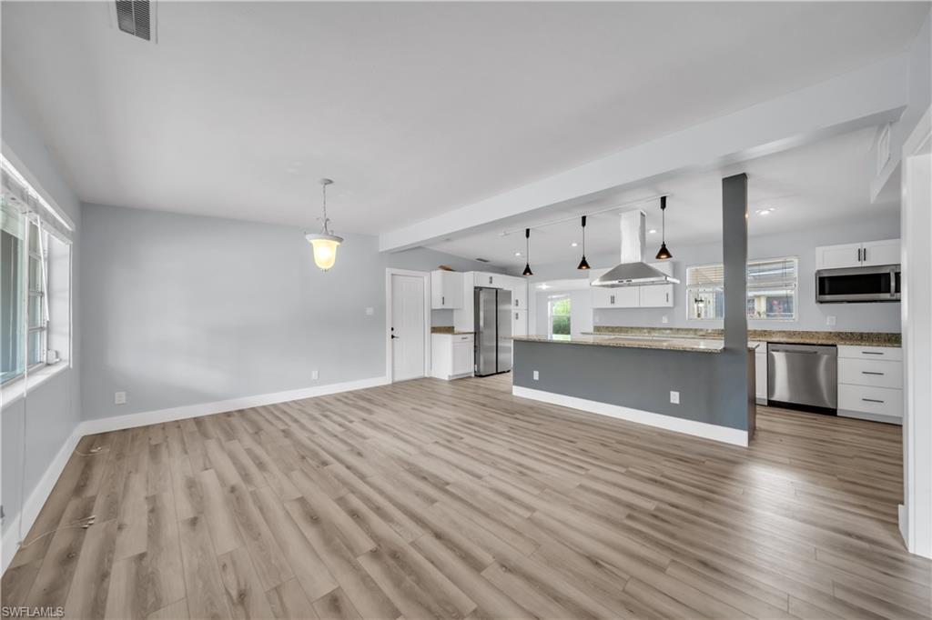 Unfurnished living room featuring baseboards and light wood finished floors