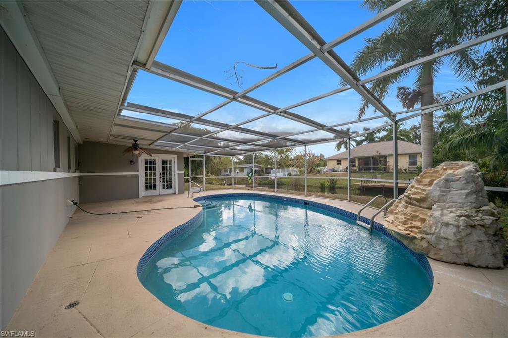 Outdoor pool featuring french doors, a sunroom, glass enclosure, and a patio