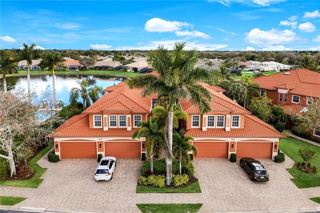 Mediterranean / spanish-style house featuring a tile roof, stucco siding, driveway, and a water view