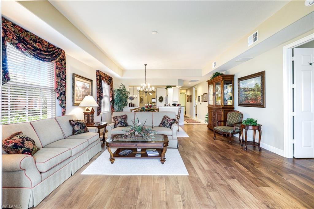 Living area with light wood-style flooring, suspended lighting, and a tray ceiling