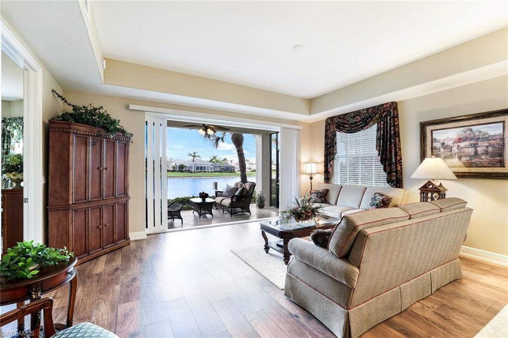 Living room featuring wood finished floors, a water view, and a raised ceiling