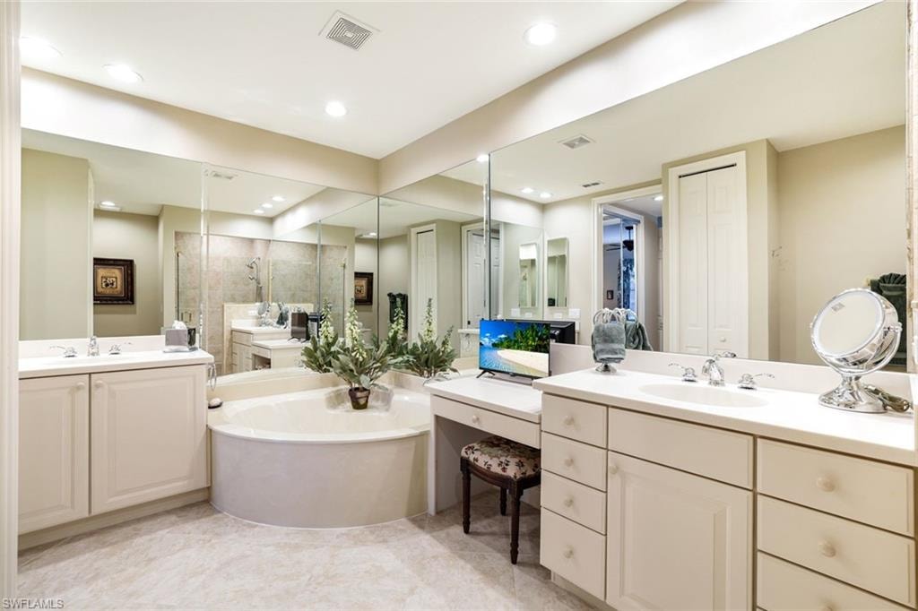 Bathroom with two vanities, a shower stall, a bath, and a walk in closet