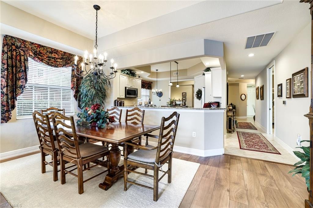 Dining space with light wood-style floors, suspended lighting, and healthy amount of natural light