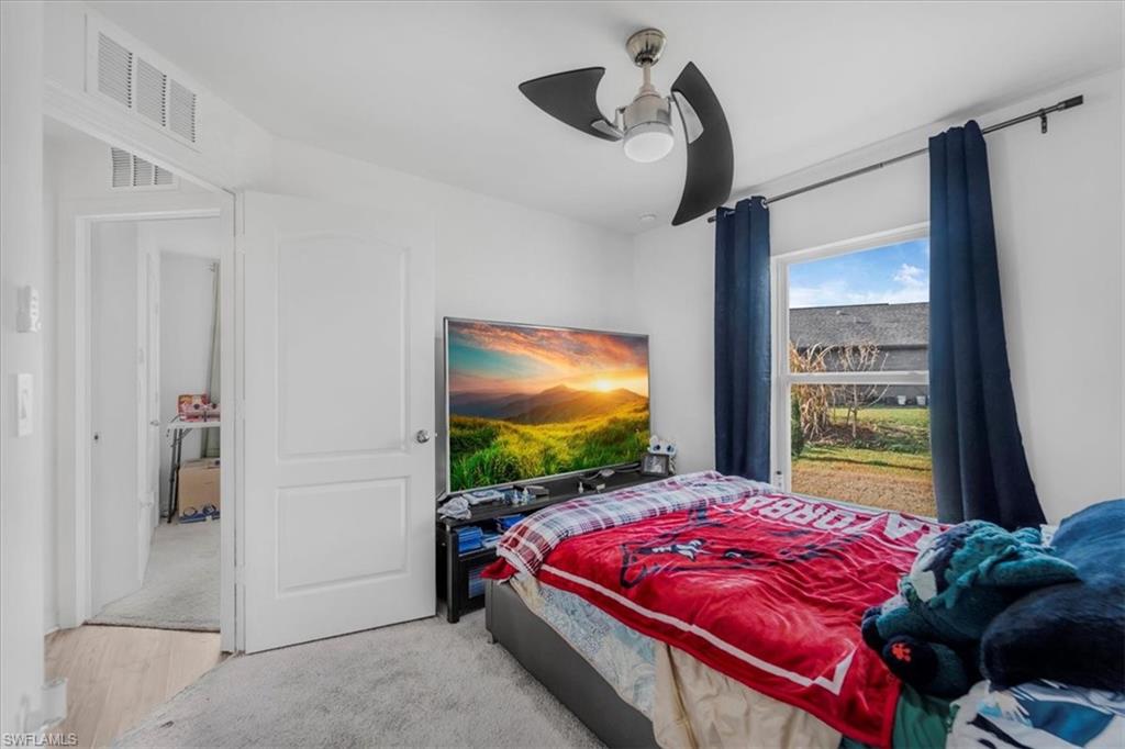 Bedroom featuring ceiling fan, light carpet, and light wood-type flooring