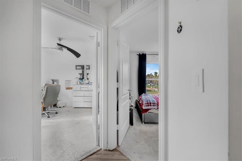 Corridor with a desk, light wood-type flooring, and light carpet