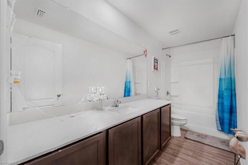 Bathroom featuring shower / bath combination with curtain, vanity, and light wood-type flooring