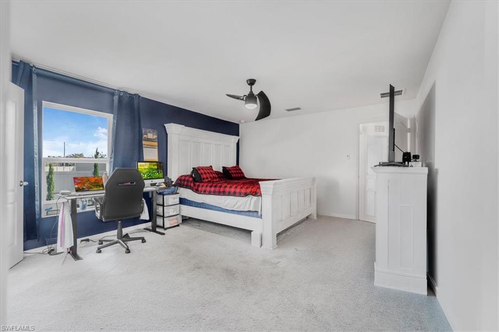 Bedroom featuring a desk, light colored carpet, and ceiling fan