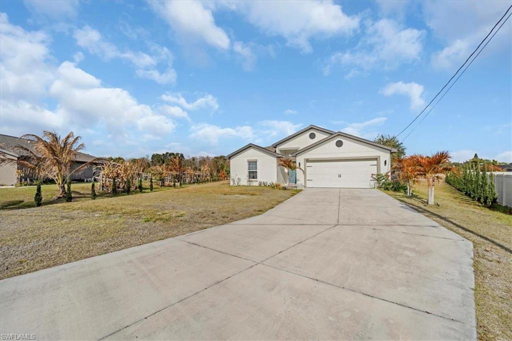Single story home featuring a front lawn, concrete driveway, a garage, and stucco siding