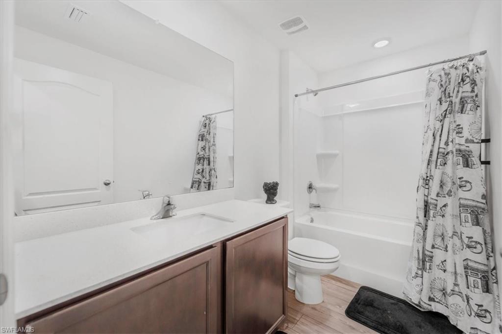 Bathroom with shower / bath combo with shower curtain, vanity, and light wood-style floors