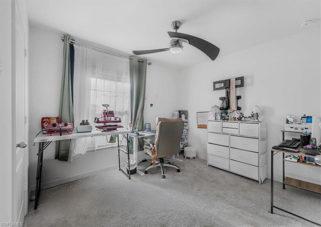 Carpeted home office featuring ceiling fan