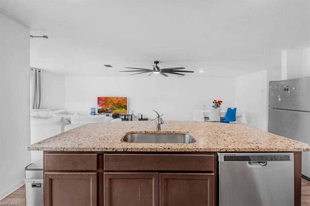 Kitchen featuring stainless steel appliances, an island with sink, light wood-style flooring, and open floor plan