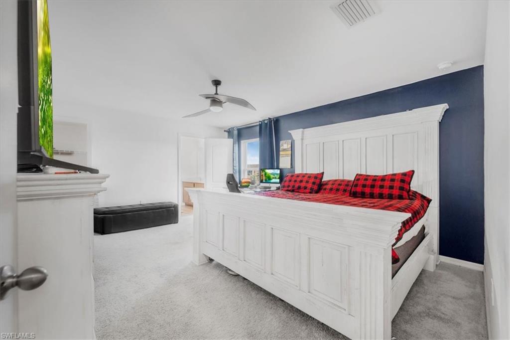 Bedroom featuring light colored carpet, ensuite bathroom, and a ceiling fan