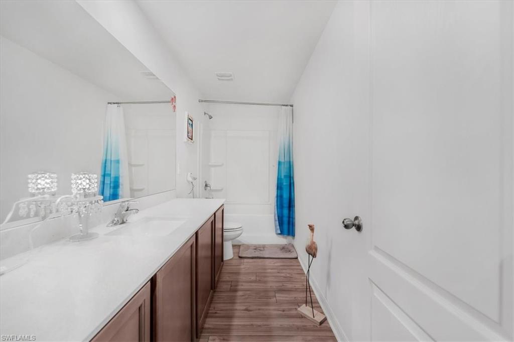 Full bath with vanity, light wood-style floors, and shower / tub combo with curtain