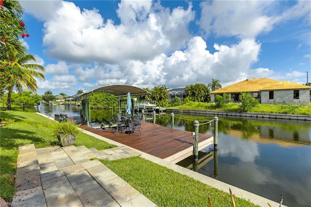 Dock area featuring boat lift, a water view, and a lawn