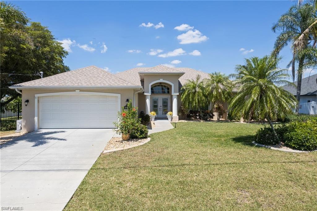 Mediterranean / spanish house with french doors, stucco siding, driveway, a garage, and a front lawn