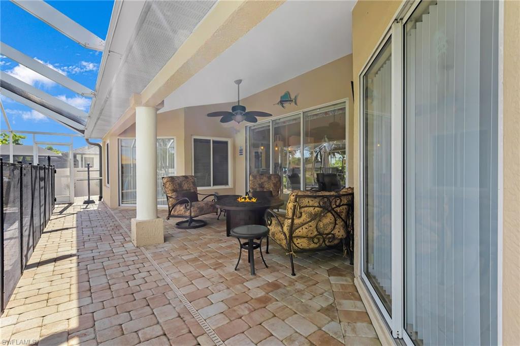 View of patio / terrace with a sunroom, glass enclosure, a ceiling fan, and a fire pit