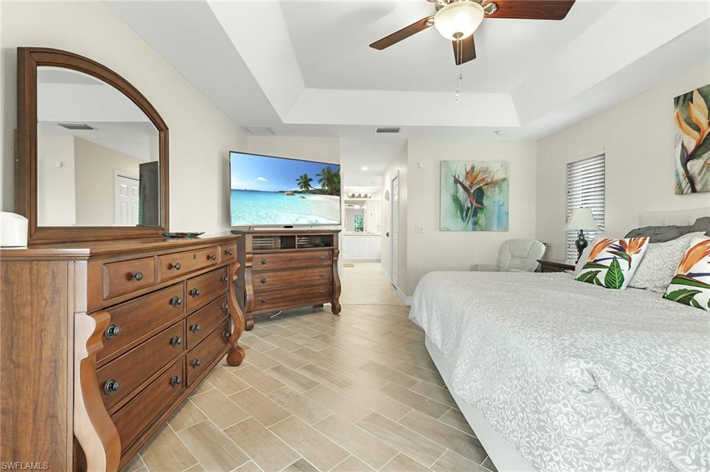 Bedroom featuring ceiling fan, wood finish floors, and a raised ceiling