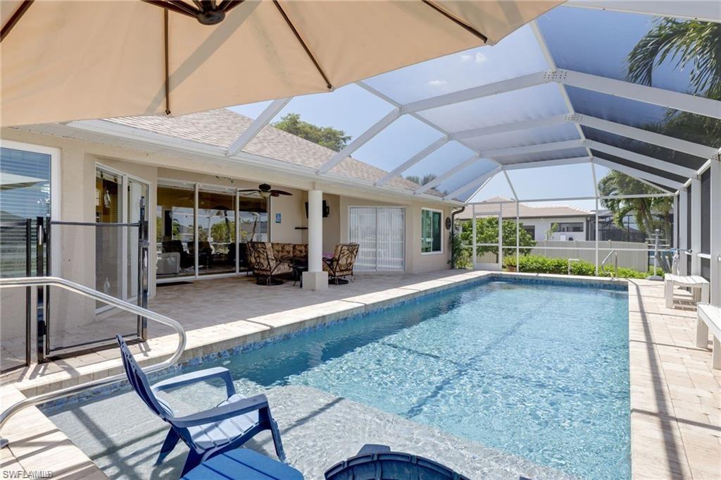 Swimming pool with a sunroom, a patio area, and glass enclosure