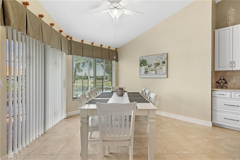 Dining room with ceiling fan, vaulted ceiling, and light tile patterned flooring