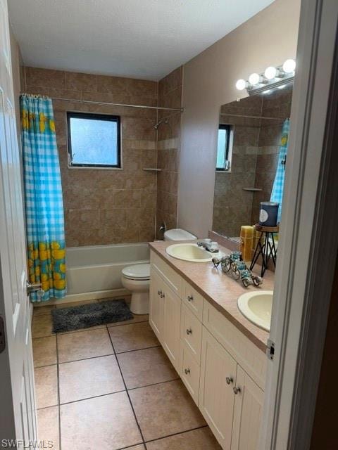 Bathroom with double vanity, shower / tub combo with curtain, light tile patterned floors, and a textured ceiling