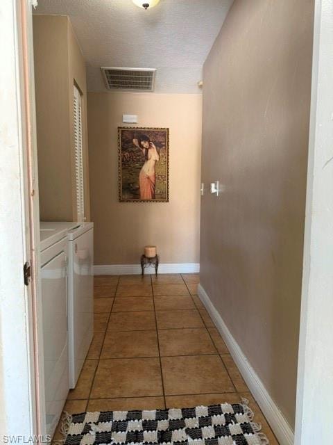 Hallway featuring a textured ceiling, separate washer and dryer, and light tile patterned floors