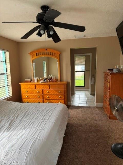 Bedroom with a ceiling fan, a textured ceiling, and light carpet