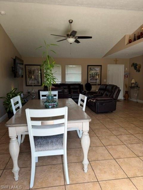 Dining space featuring a ceiling fan, lofted ceiling, and light tile patterned floors