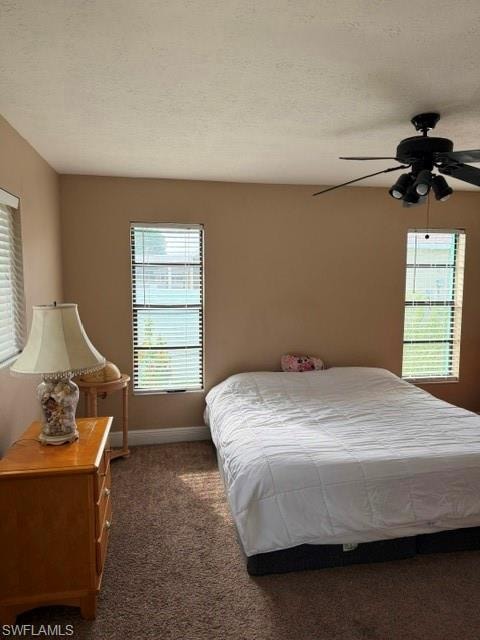 Bedroom featuring dark carpet, a textured ceiling, and ceiling fan