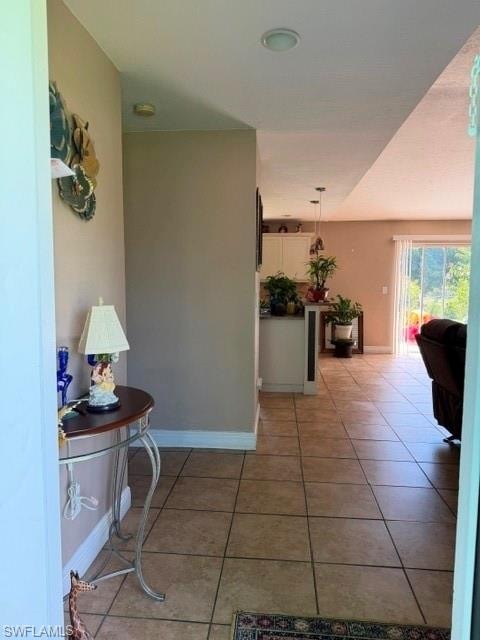 Hallway with light tile patterned flooring and baseboards