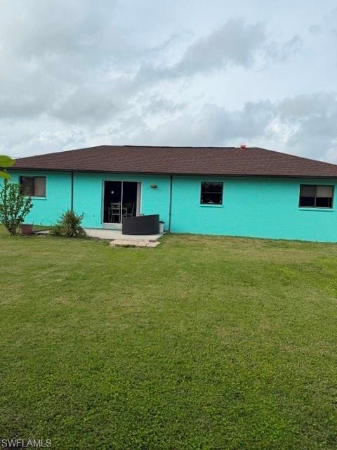Back of property featuring a yard, a patio, and roof with shingles