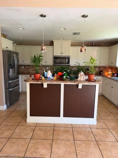 Kitchen featuring a kitchen island, light stone countertops, fridge, light tile patterned floors, and tasteful backsplash
