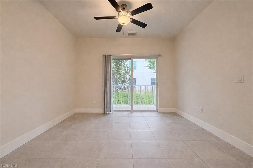 Kitchen featuring white cabinets, stainless steel appliances, light stone counters, a center island, and light tile patterned floors