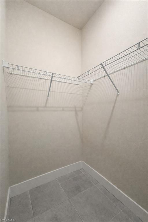 Empty room featuring baseboards and light tile patterned floors