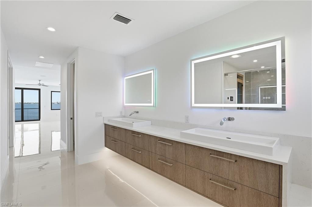Bathroom featuring double vanity, recessed lighting, and a shower stall