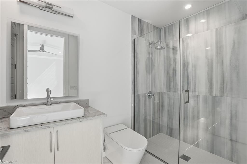 Full bathroom with a marble finish shower, vanity, and recessed lighting