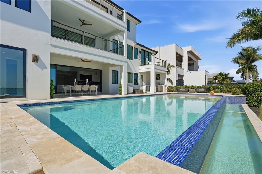View of pool featuring an infinity pool, patio surround, and a balcony