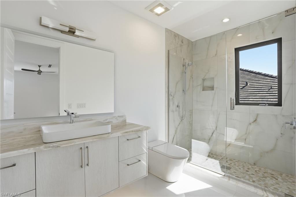 Full bathroom with vanity, a marble finish shower, recessed lighting, and a ceiling fan