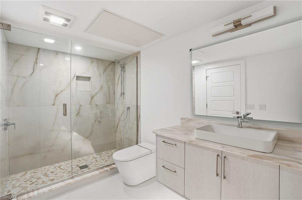 Bathroom featuring vanity and a marble finish shower