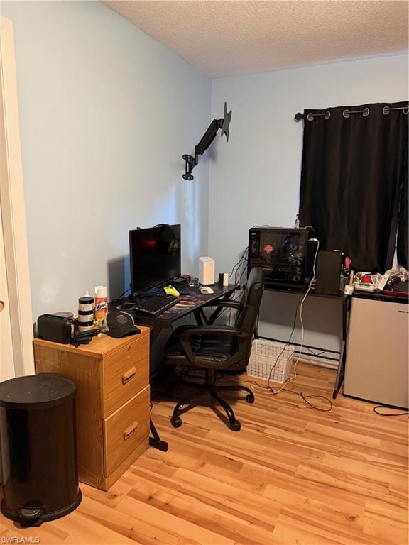Office space featuring light wood finished floors and a textured ceiling