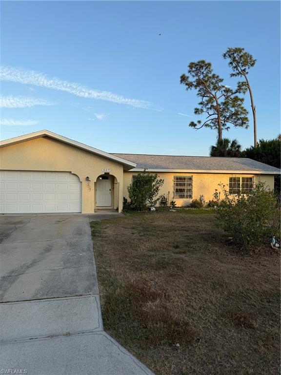 Ranch-style home with stucco siding, concrete driveway, a garage, and a front lawn