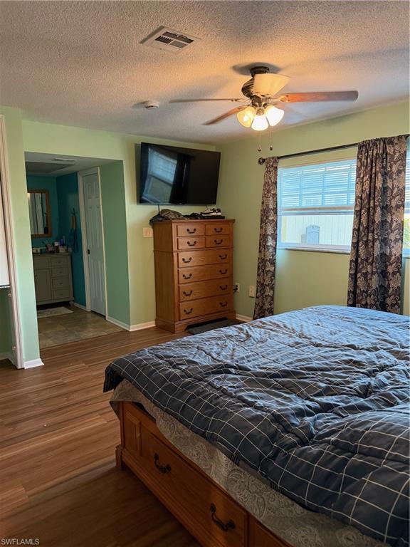 Bedroom with dark wood-style floors, a textured ceiling, and a ceiling fan
