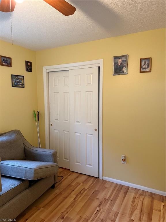 Sitting room with ceiling fan, a textured ceiling, and light wood-style floors
