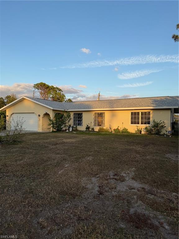 Single story home with stucco siding, a front yard, and an attached garage