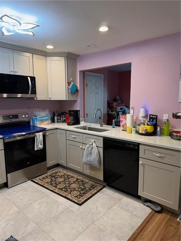 Kitchen with range, gray cabinets, dishwasher, recessed lighting, and light stone countertops