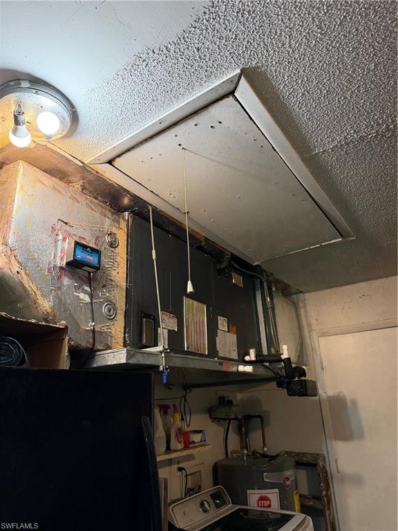 Detailed view of washer / dryer, heating unit, water heater, and a textured ceiling