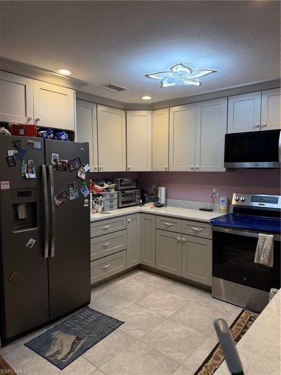 Kitchen featuring refrigerator, stove, gray cabinetry, a textured ceiling, and recessed lighting