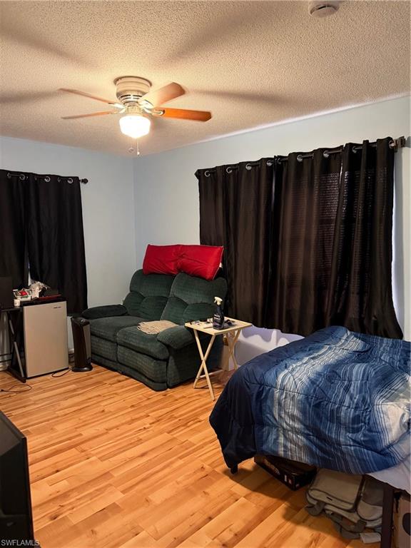 Bedroom featuring light wood-style floors, a textured ceiling, and a ceiling fan