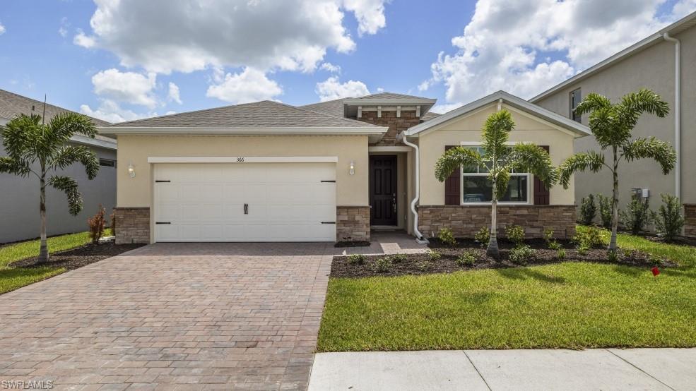 Model home. Ranch-style house with stone siding, stucco siding, decorative driveway, a front yard, and a garage