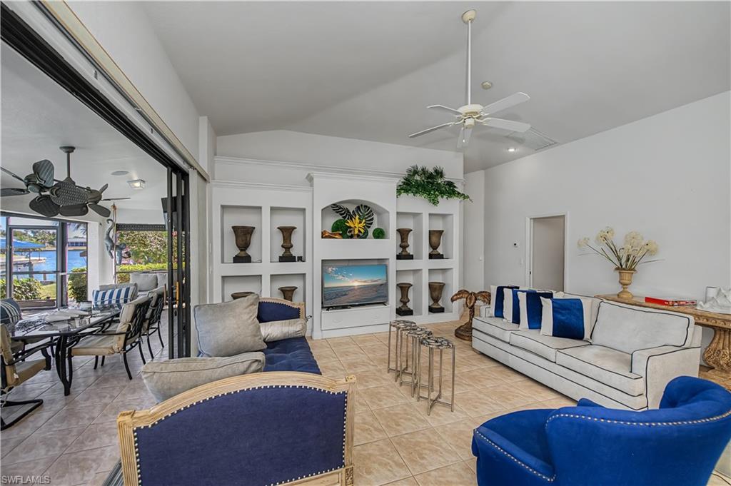 Living area with a ceiling fan, vaulted ceiling, built in shelves, and light tile patterned flooring